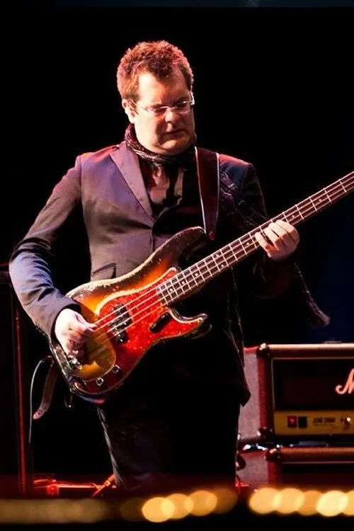 Jon Noyce interpretando a Bass